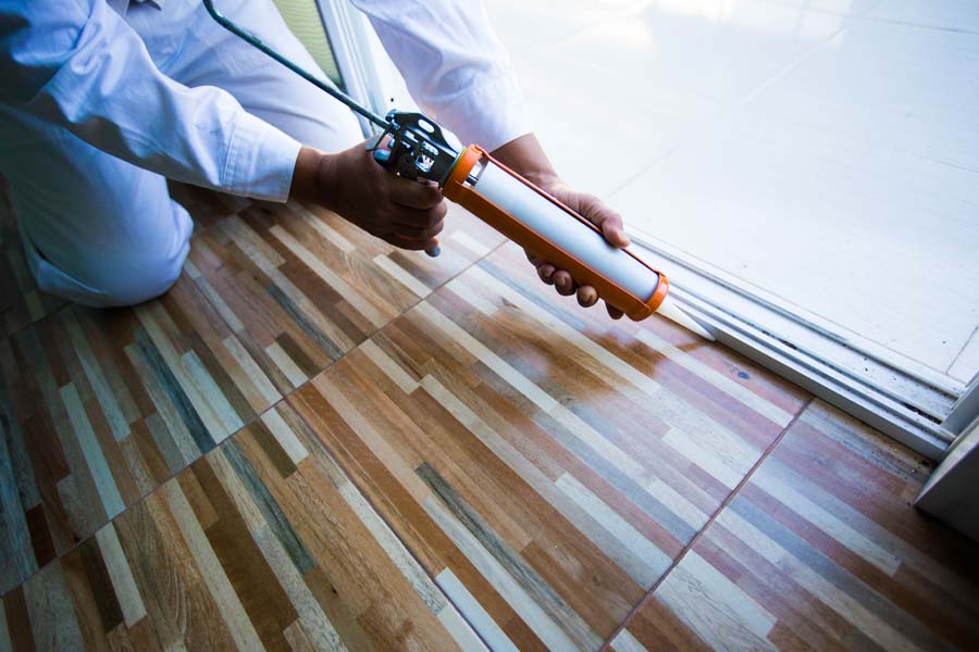 A man is caulking his wood flooring in Lawrence