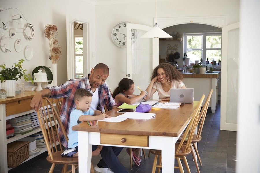 Parents Helping Children With Homework At Table.